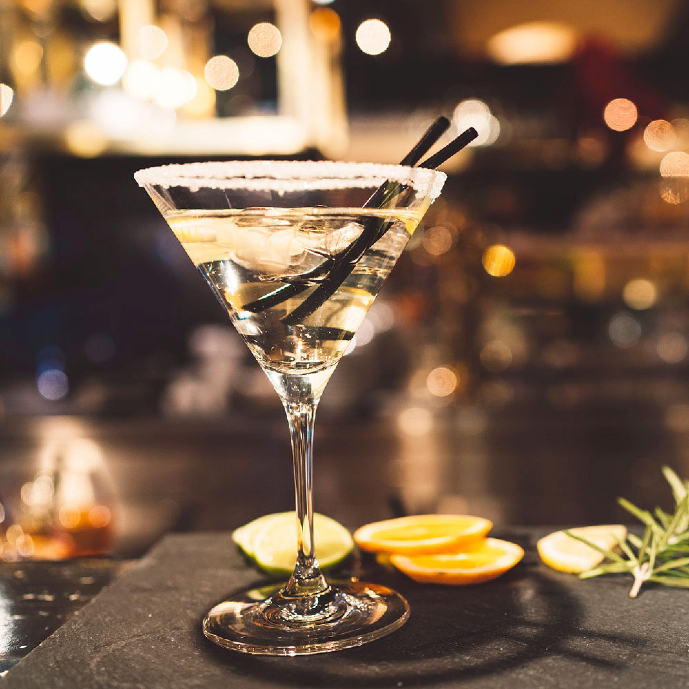 Cocktail glass with sliced lemons and a sprig of rosemary set at its base.